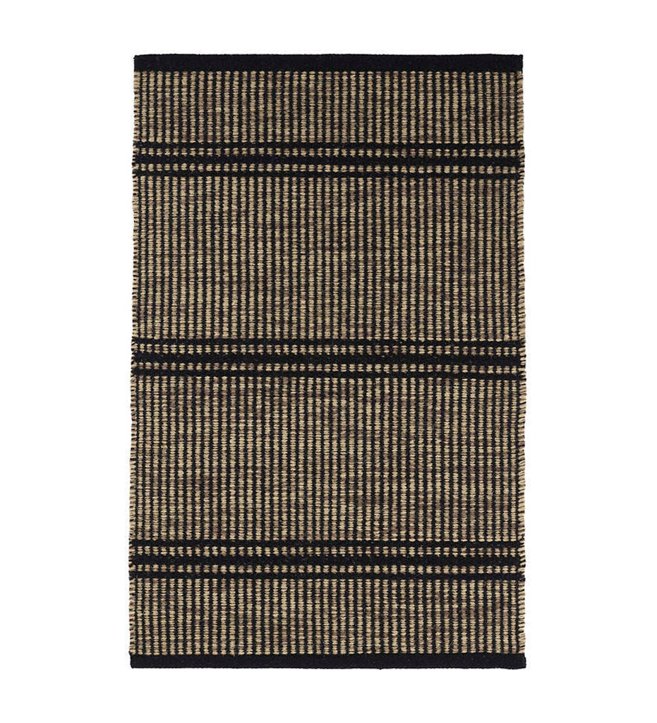 Malta Camel Woven Wool Rug displayed with a basket, throw, and slip ons. 