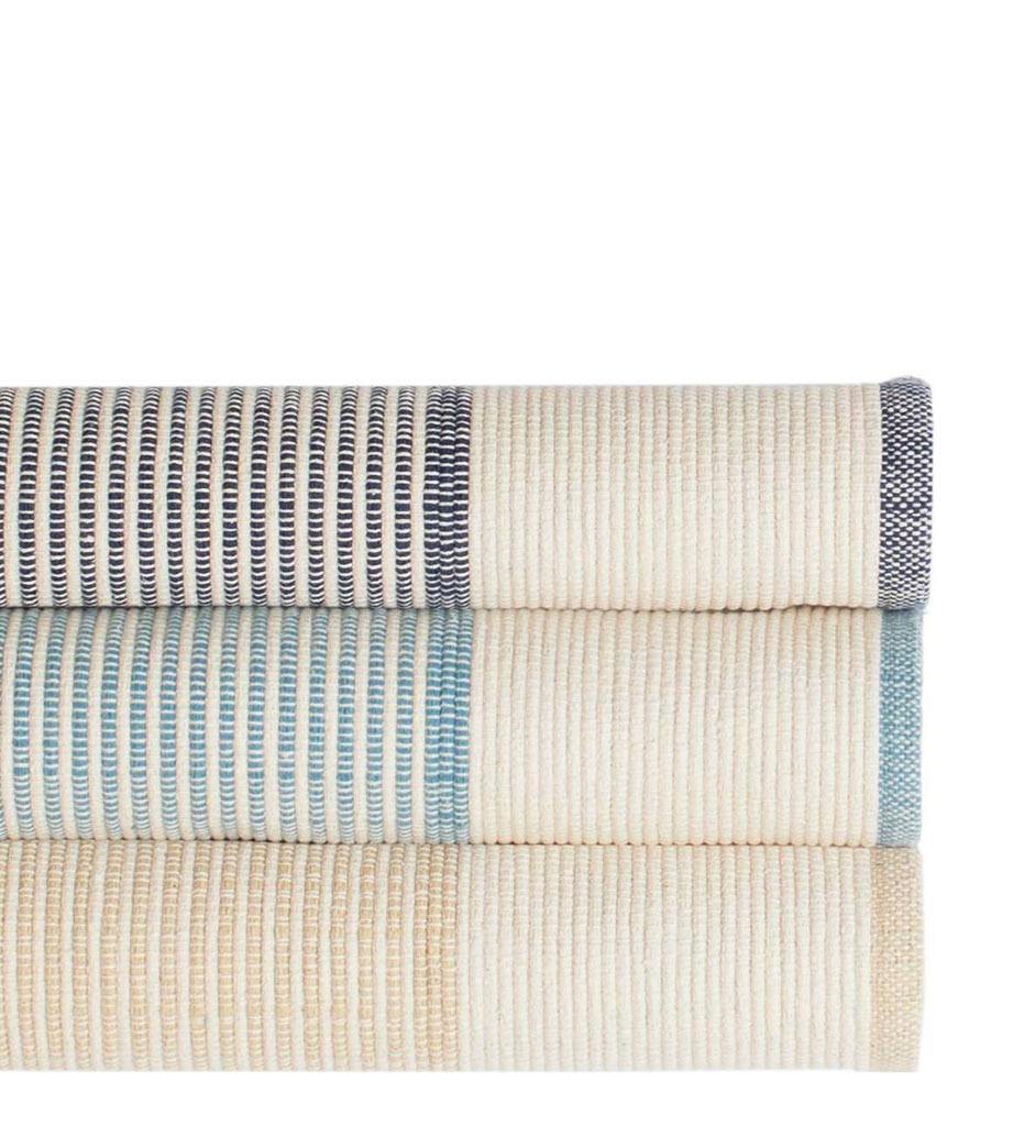 lifestyle, La Mirada Woven Cotton Rug in Navy, Asiatic Blue, and Wheat (Top to Bottom)